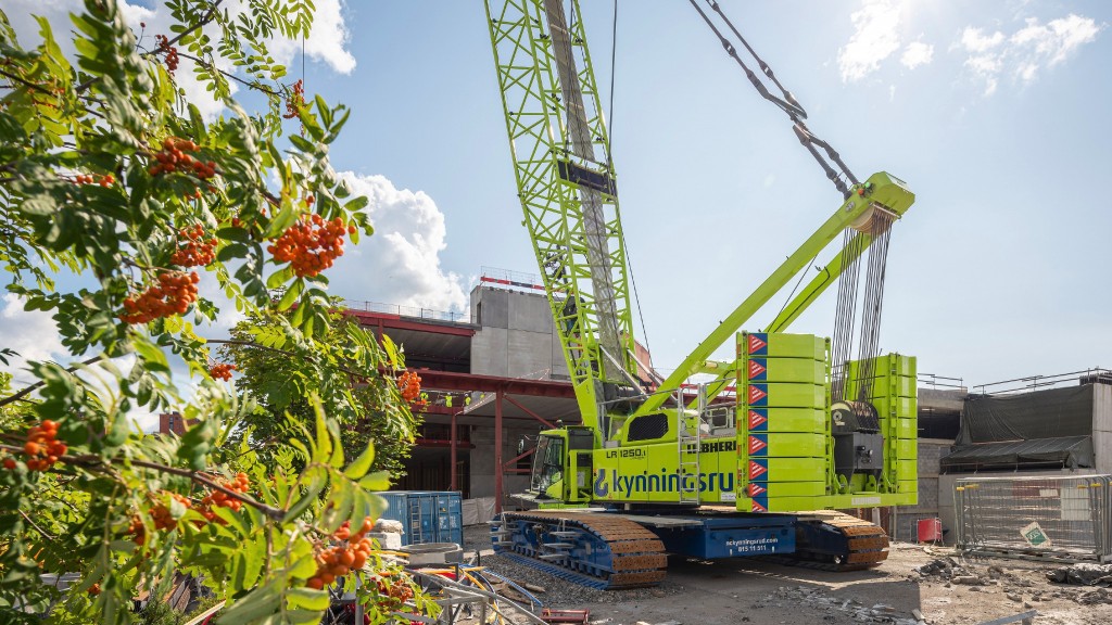 A green crawler crane is parked on a job site