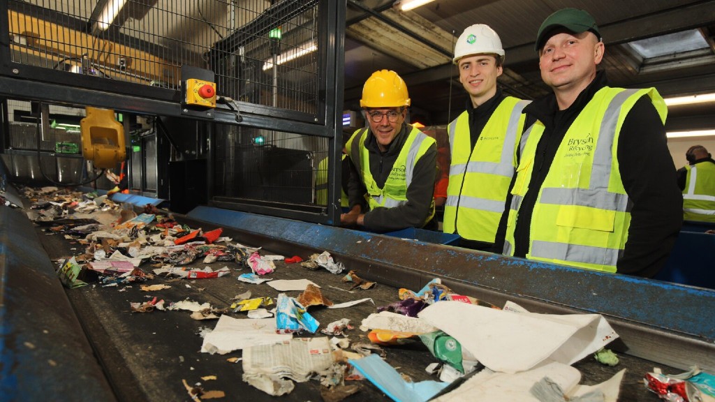 Byrson Recycling employees stand next to a sorting robot
