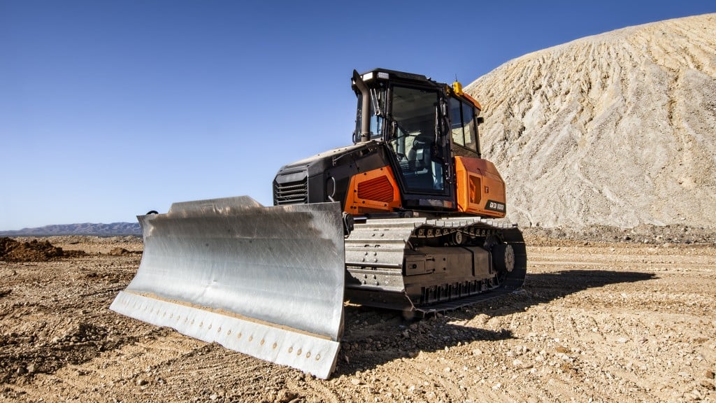 An orange and black Doosan crawler dozer on a desert site.