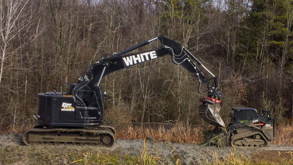 A Ken White Construction excavator and compact track loader parked on a trail