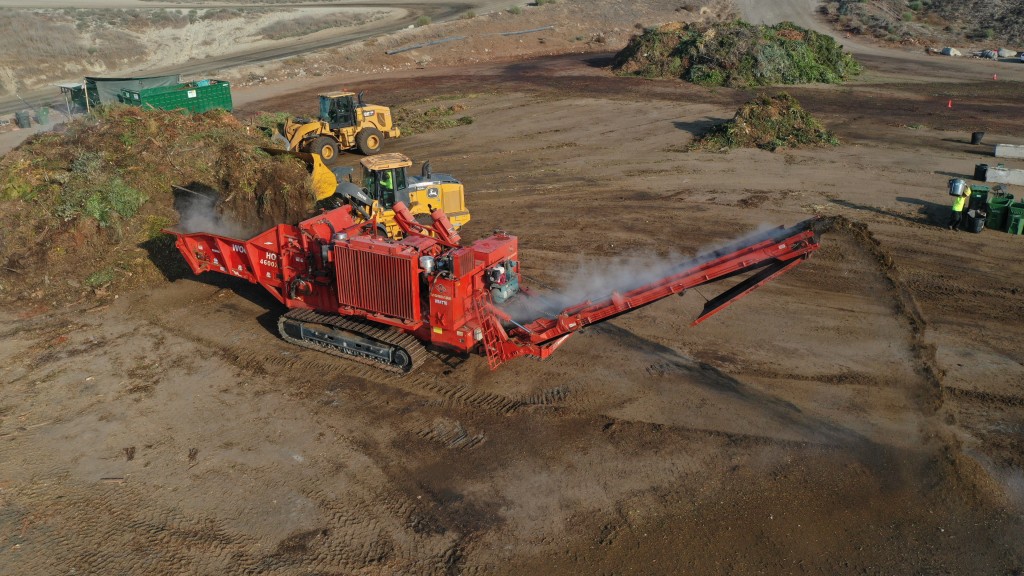 A horizontal grinder grinding organic waste on a job site