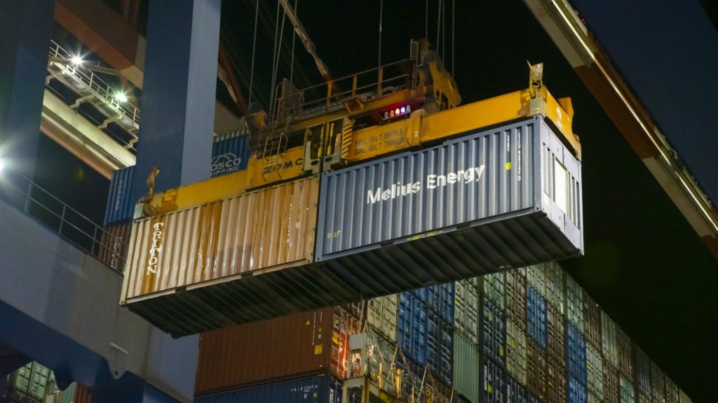 A shipping container in the middle of being loaded onto a ship