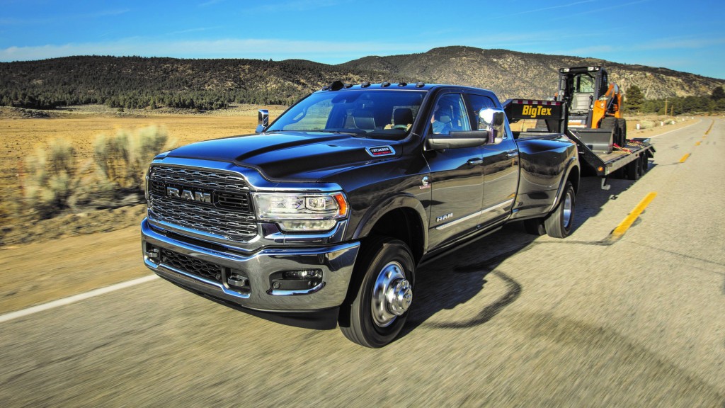 A Ram pickup truck towing a piece of earthmoving equipment