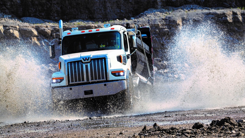 A dump truck splashes through a large puddle