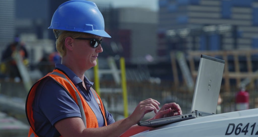 An operator works on a laptop on a job site