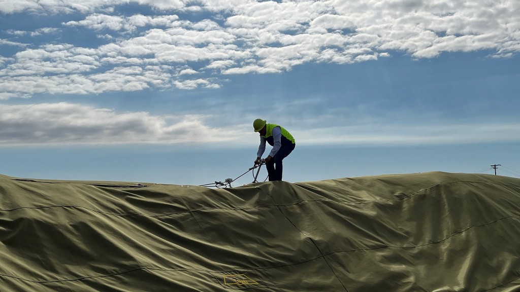 A worker probes covered compost soil