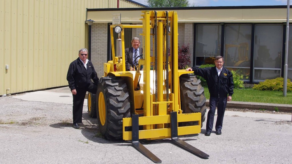 All three co-founders of Sellick Equipment around a converted forklift