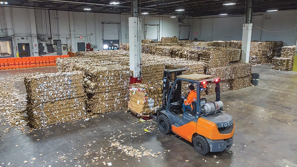 A forklift moves bales of mixed cardboard