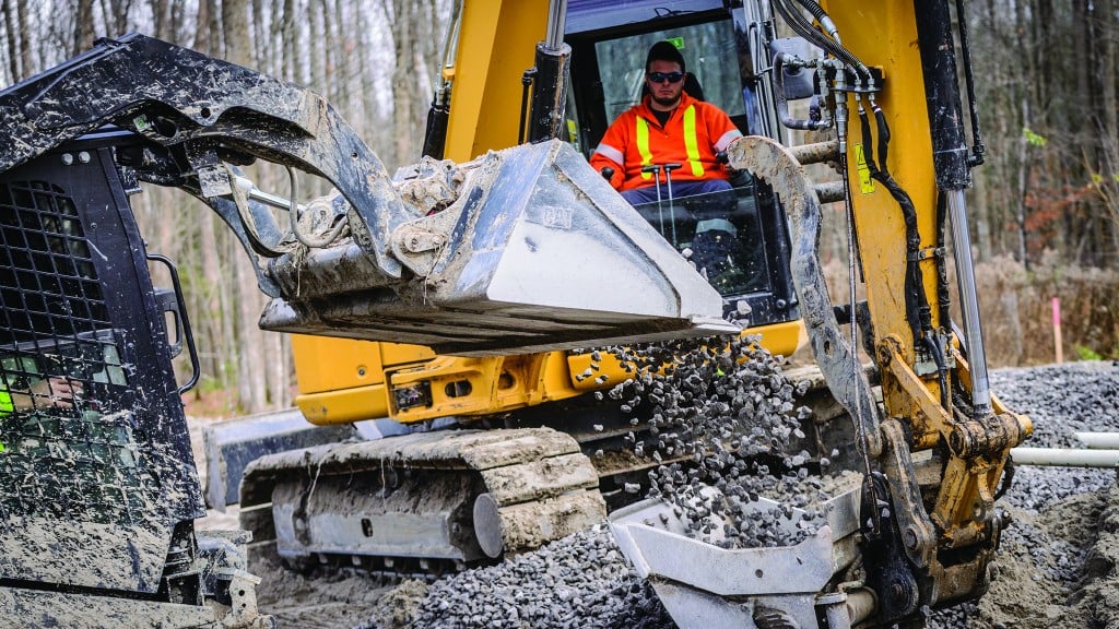 An operator in an excavator transfers material to another machine bucket