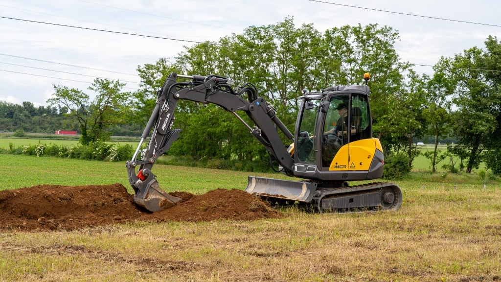 An excavator skid steer combination moves dirt on a job site