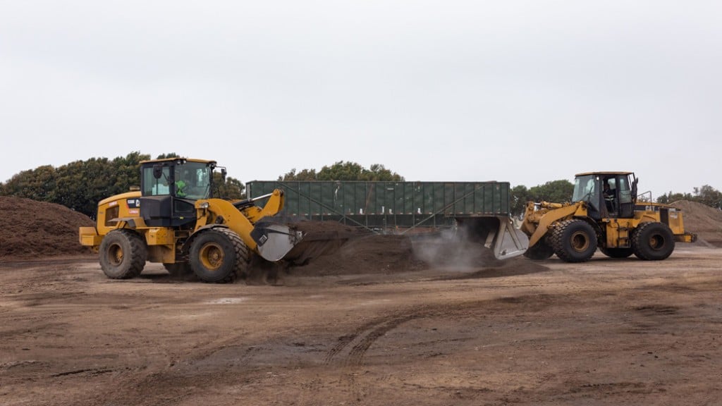 Two tractors move mulch on a job site