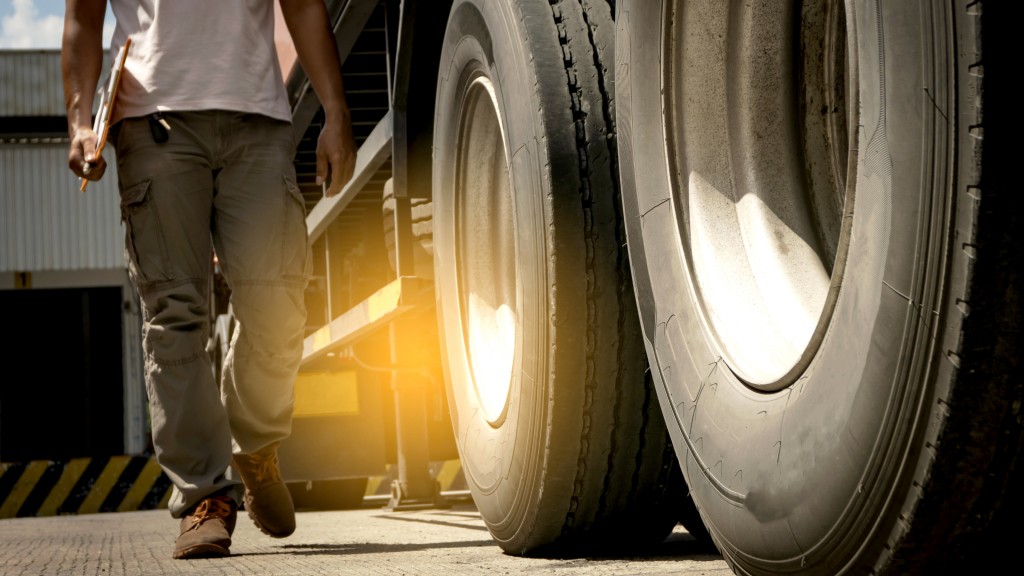 A driver walks along the side of a truck