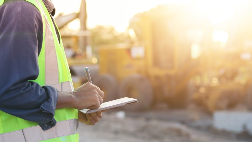An operator holds a note pad on a job site