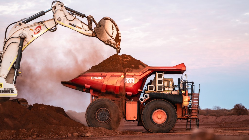 An excavator fills a rigid dump truck with dirt