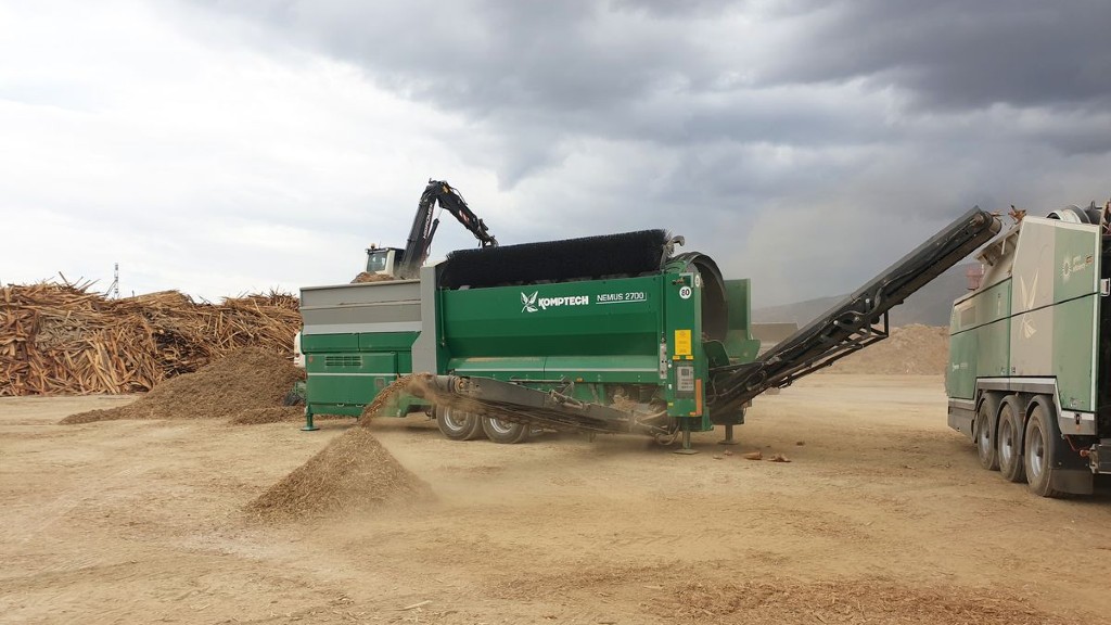 A green trommel screen operates on a job site