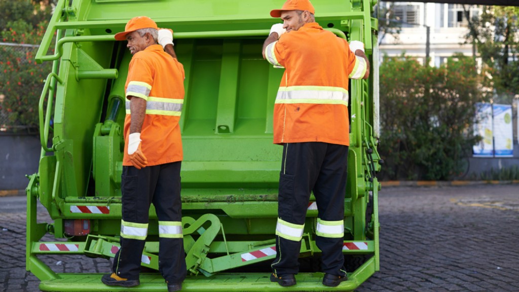 Two collection workers stand on the back of a truck