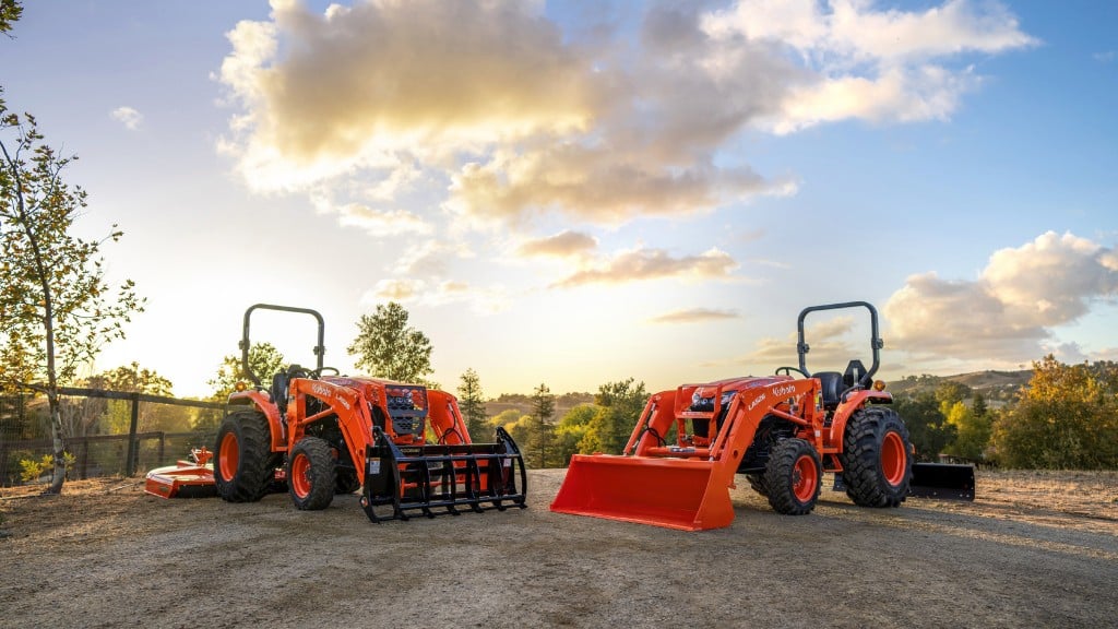 Two tractors are parked in a dirt parking lot