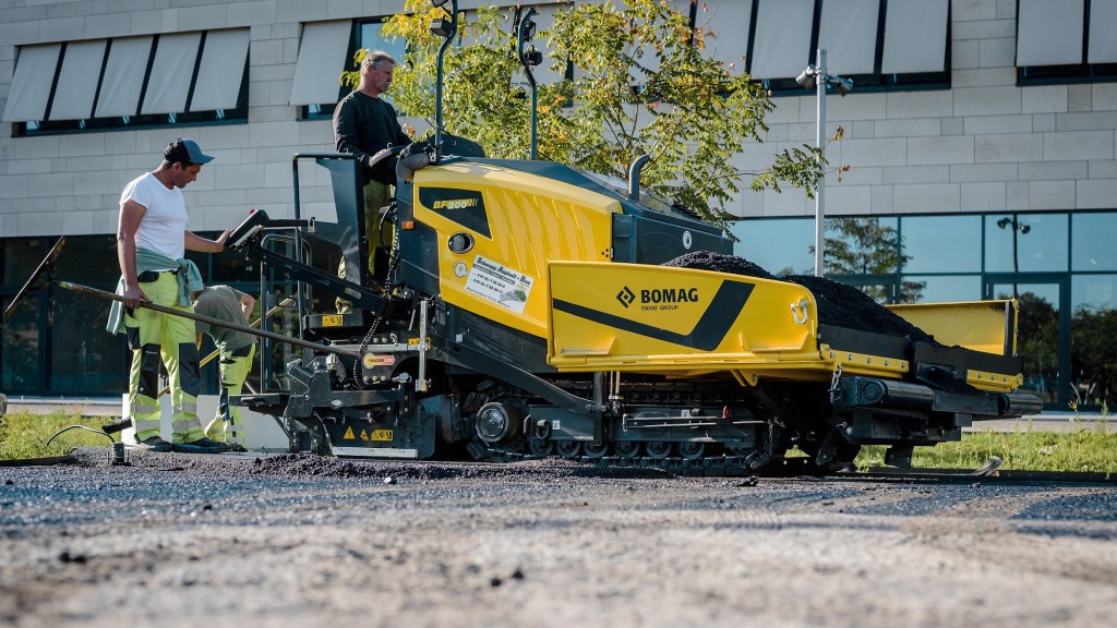 A paver operates on a job site near a building