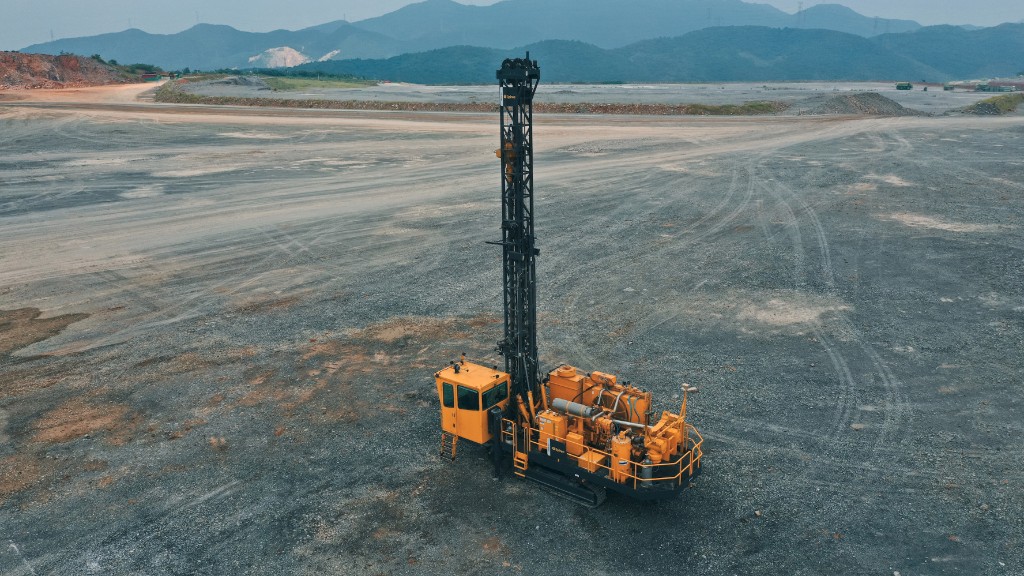 A drill rig operates on a grassy job site