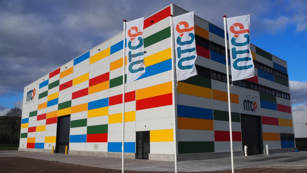 Flags blow in the wind in front of a colourful building