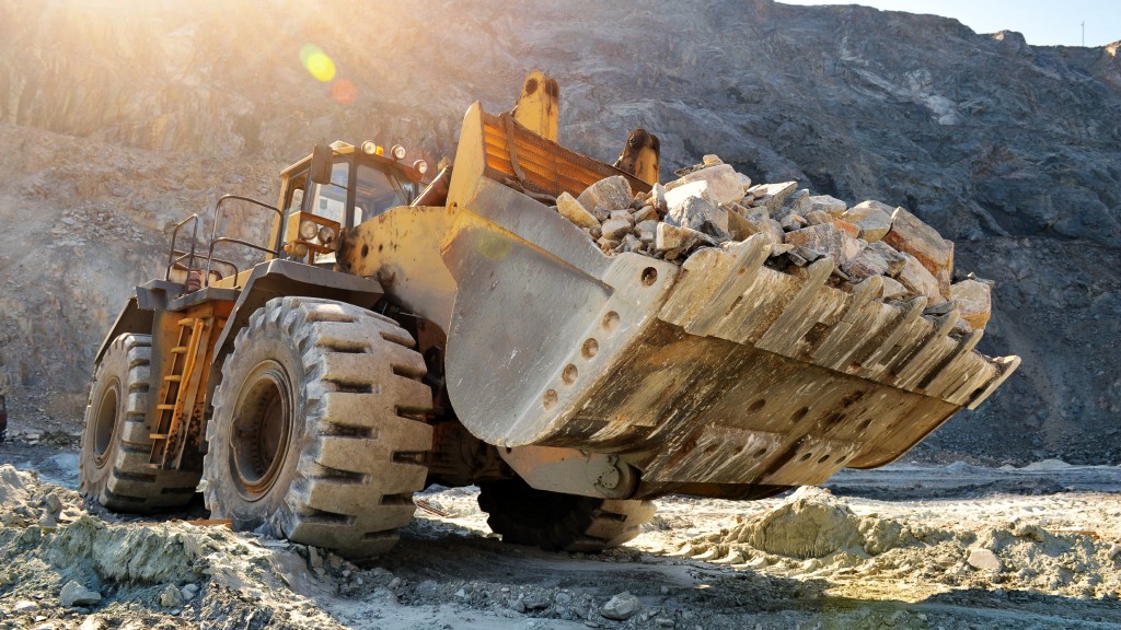 A wheel loader full of rocks is parked on a job site