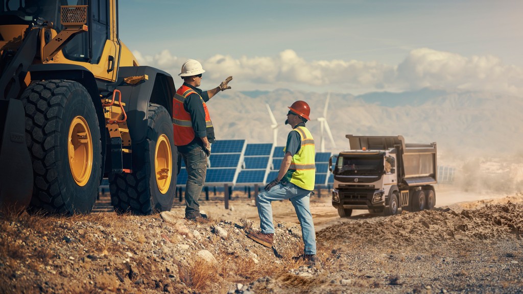 Two workers communicate near a dirt road