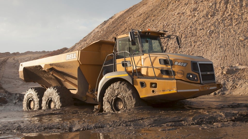 An articulated dump trucks drives through a mud puddle