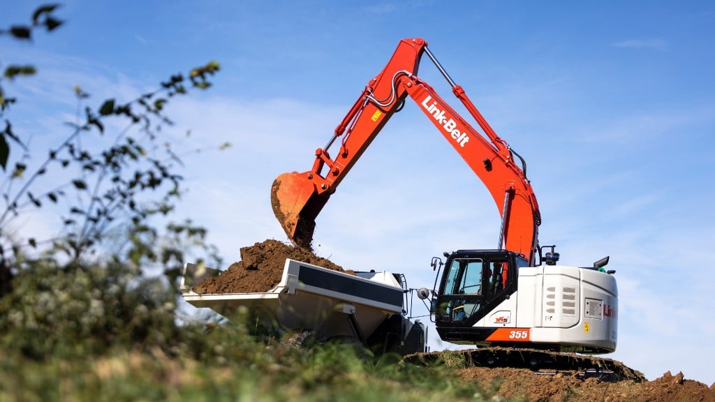 An excavator loads a truck with dirt on a job site