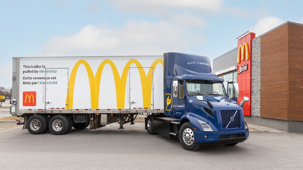 A McDonalds branded electric truck is parked outside a restaurant