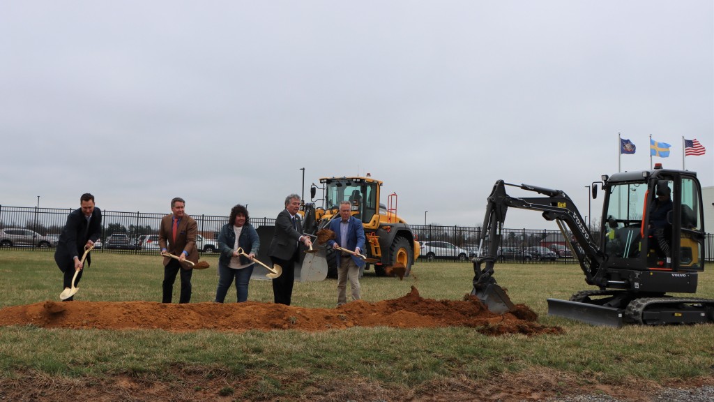 People and an excavator dig a ditch in a field