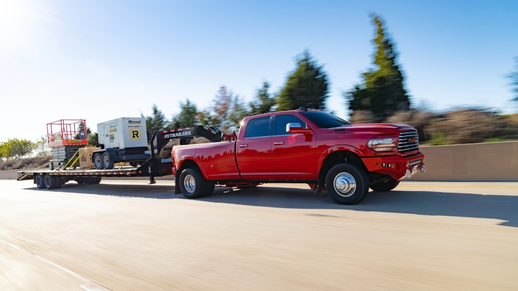 A truck pulls a trailer with equipment down a highway