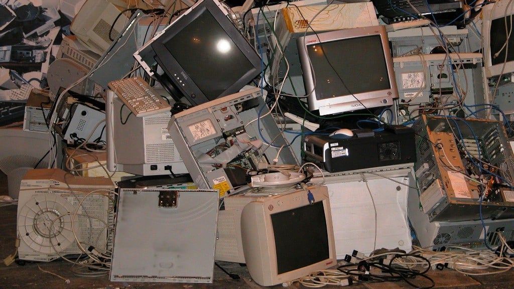 Old computers and electronics are stacked in a pile