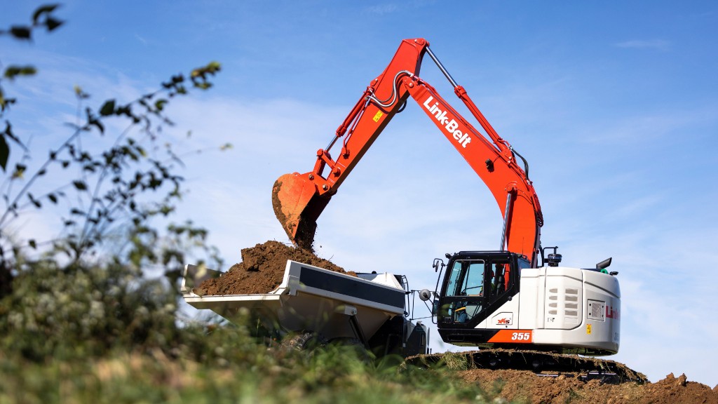 An excavator dumps dirt into a truck