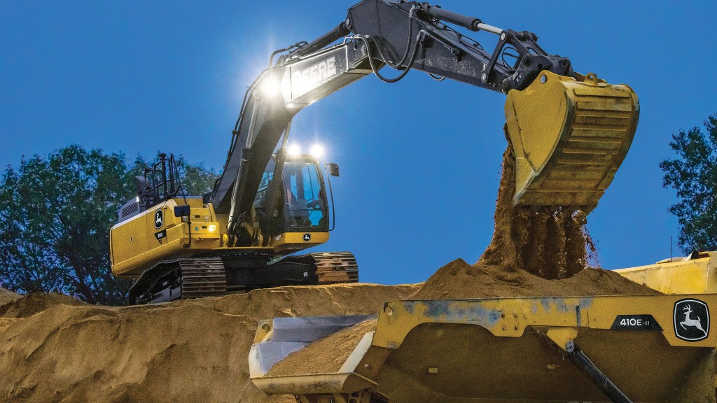 A John Deere excavator on a hill moving dirt