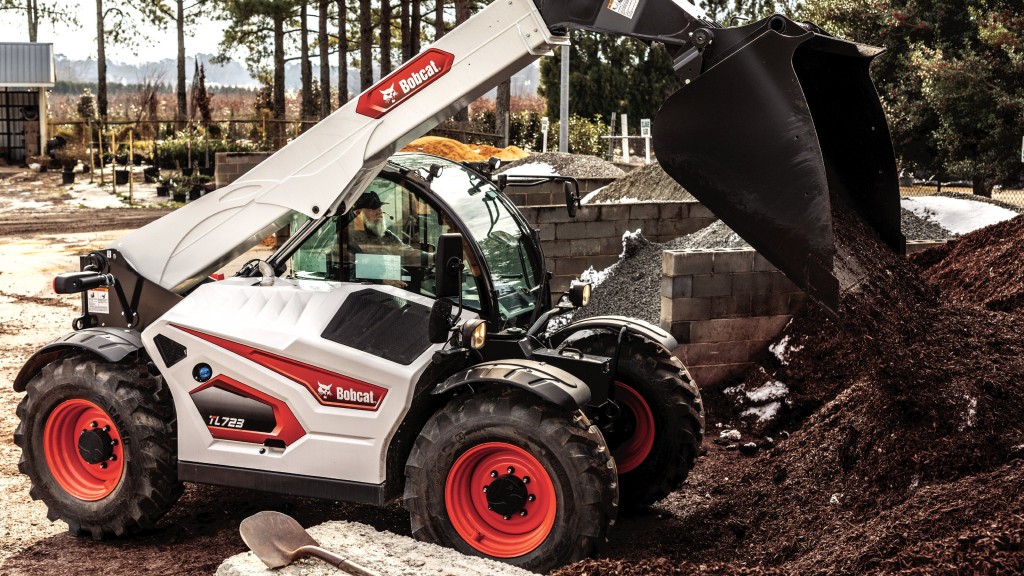 A telehandler with a bucket dumps dirt on a job site