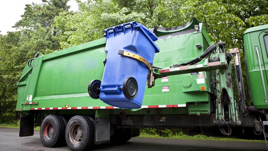 A collection truck lifts up a waste bin