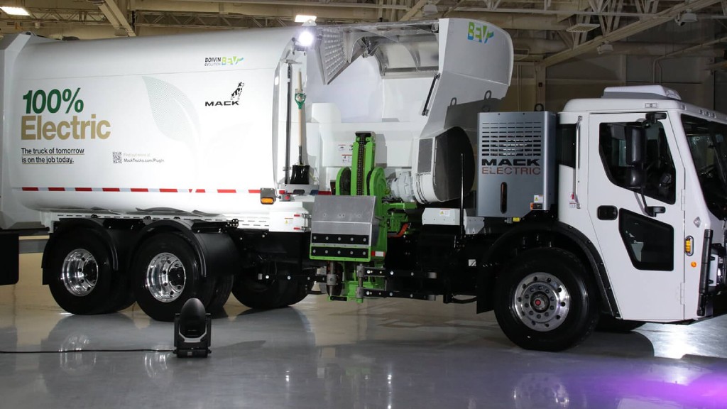 An electric collection truck is parked inside a garage