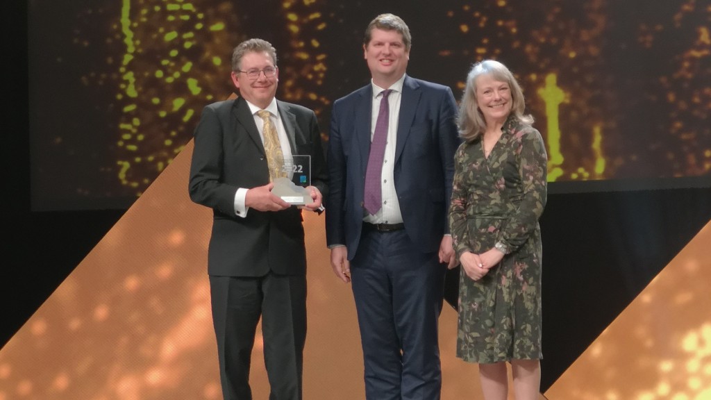 Several people stand on a stage with an award