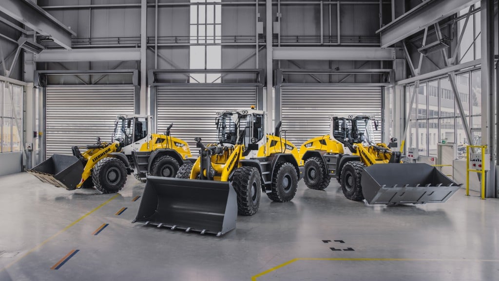 Three wheel loaders are parked in a garage.