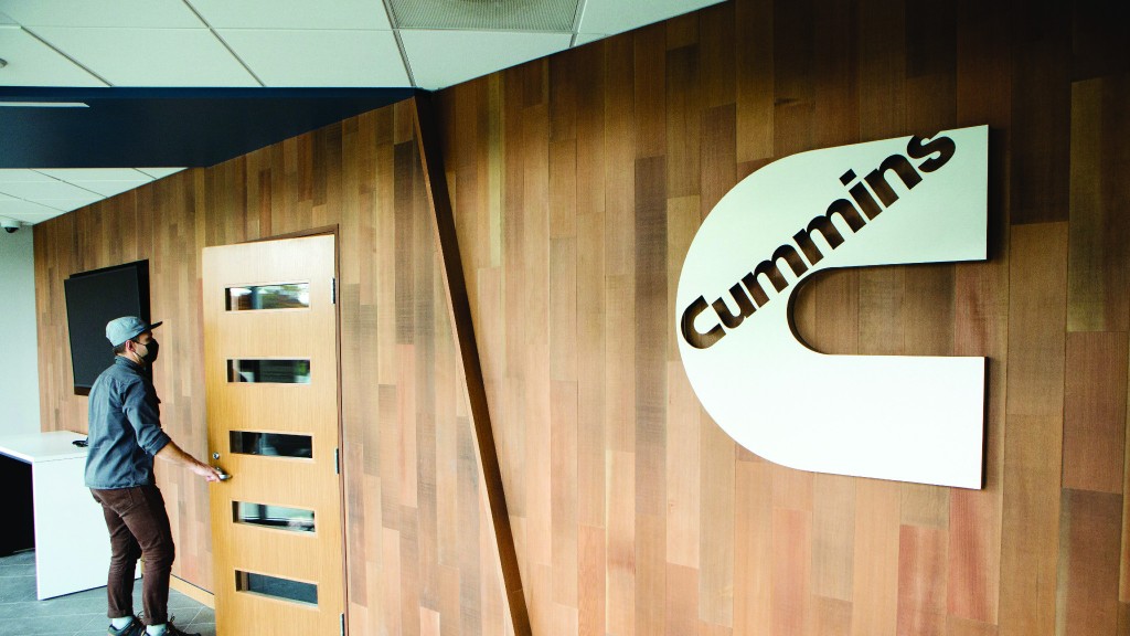 A man walks through a doorway next to a Cummins logo