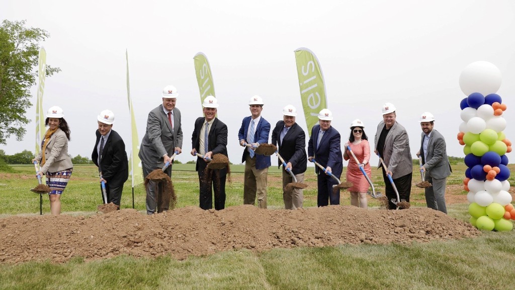 Several people dig in the dirt with shovels