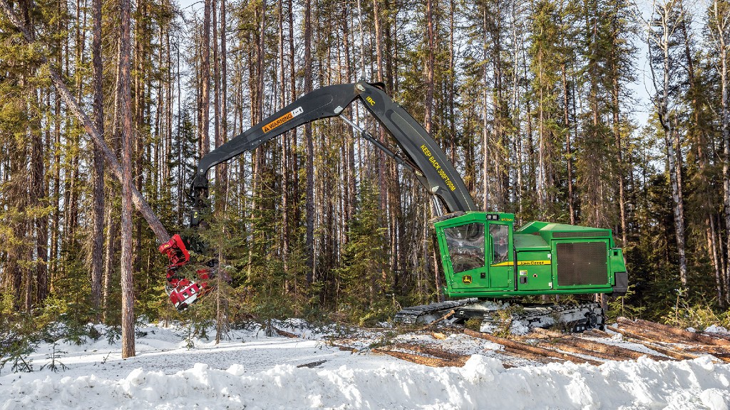 A tracked harvester harvests logs at a job site