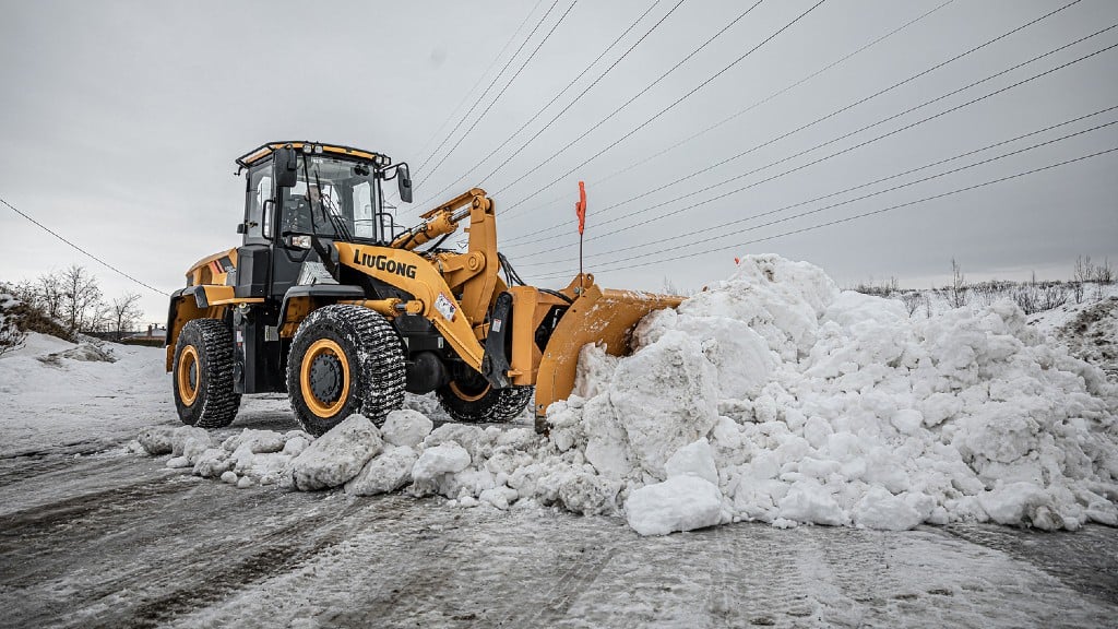 A wheel loader pushes snow on a road