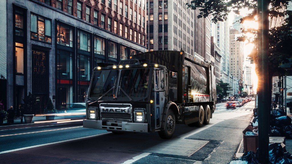 An electric collection truck drives down a street