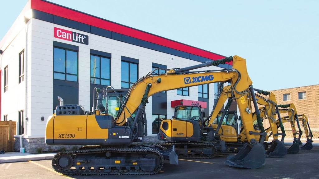 Several excavators are parked outside a dealership