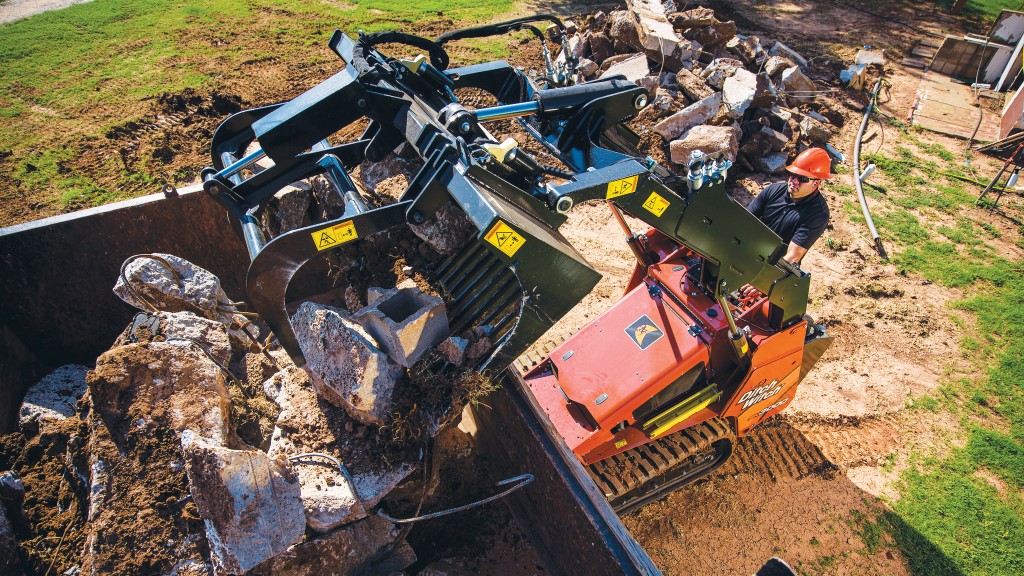 A stand-on loader fills a container C&D waste