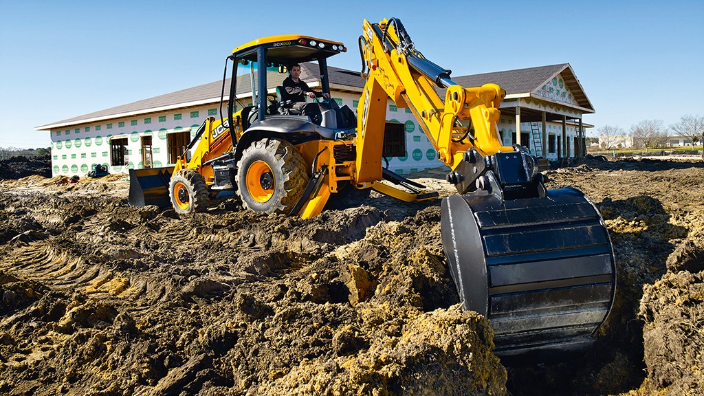 A backhoe loader digs dirt on the job site