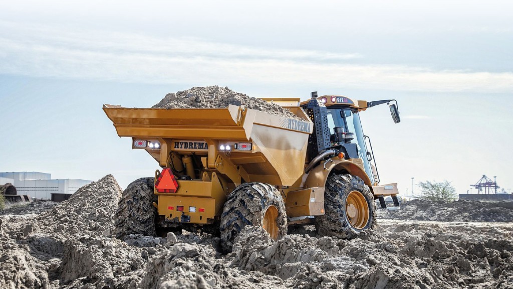 A dump truck drives through a lot of mud