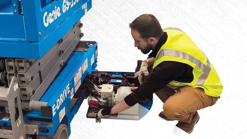 A technician checks the oil containment system of a scissor lift