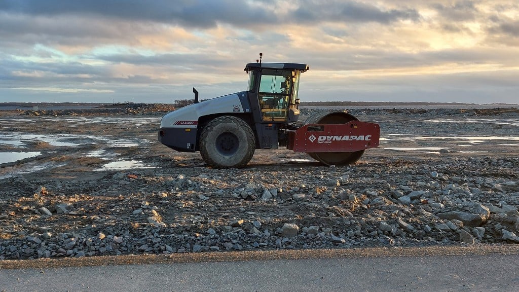 A Dynapac soil roller on a flat plain of rock and soil